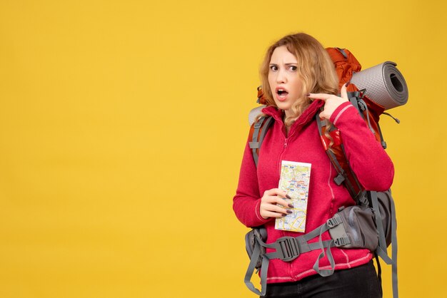 Vue de dessus de la jeune fille voyageuse confuse dans un masque médical rassemblant ses bagages et tenant la carte