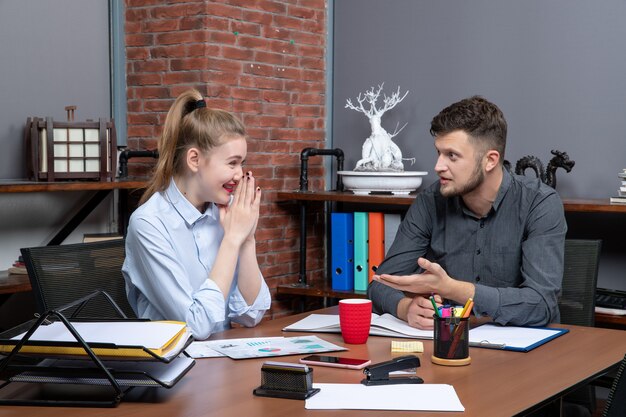 Vue de dessus de jeunes collègues de gestion assidus discutant d'un problème avec une expression faciale surprise dans un environnement de bureau