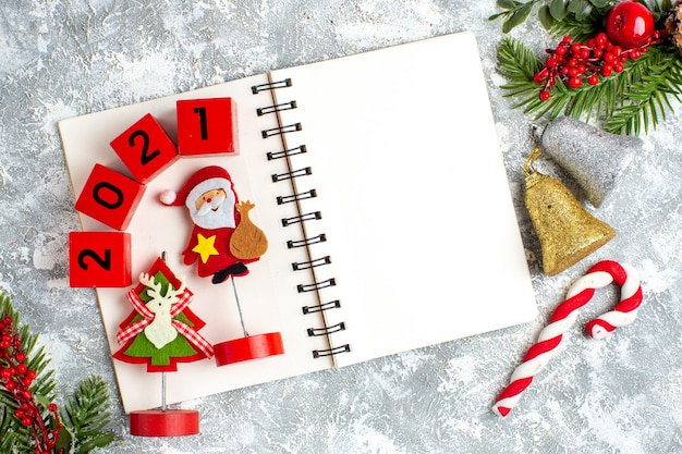 Vue de dessus des jouets de noël blocs de bois sur le bloc-notes cloches de noël bonbons de noël sur une table blanche grise