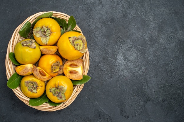 Vue de dessus kakis doux frais à l'intérieur du panier sur le goût mûr de fruits de table sombre