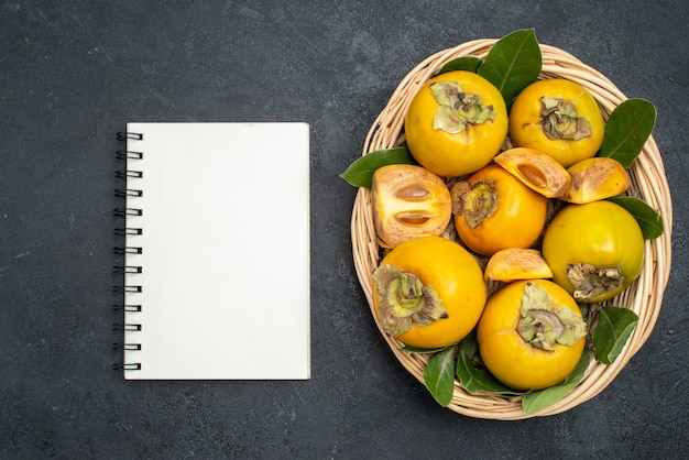 Photo gratuite vue de dessus kakis doux frais à l'intérieur du panier sur la table sombre fruits mûrs