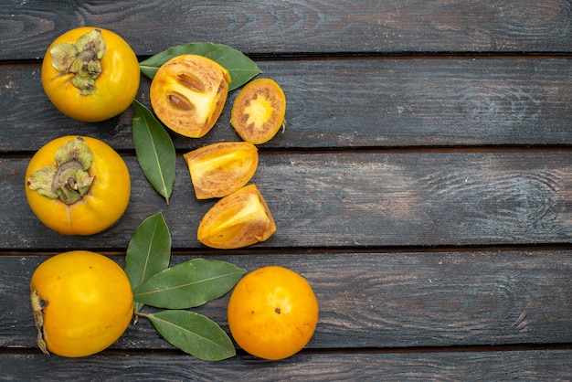 Photo gratuite vue de dessus kakis doux frais sur une table rustique en bois, fruits mûrs moelleux