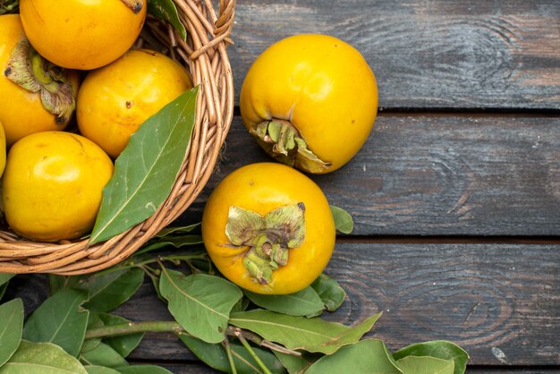 Vue de dessus kakis frais à l'intérieur du panier sur plancher en bois fruits mûrs mûrs