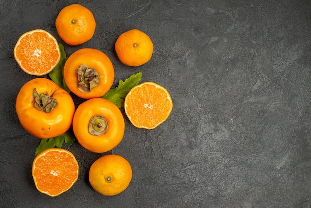 Vue de dessus des kakis frais avec des mandarines sur fond sombre