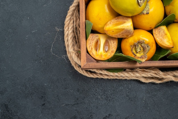 Photo gratuite vue de dessus kakis sucrés frais à l'intérieur de la boîte sur le goût de la table sombre fruits mûrs