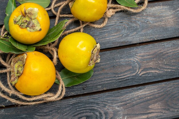 Vue de dessus kakis sucrés frais sur plancher en bois goût de fruits mûrs