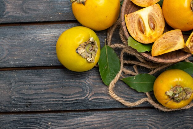 Vue de dessus kakis sucrés frais sur plancher rustique en bois goût fruits mûrs