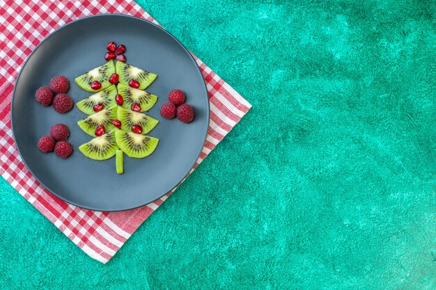 Vue de dessus des kiwis frais tranchés avec des framboises sur fond vert