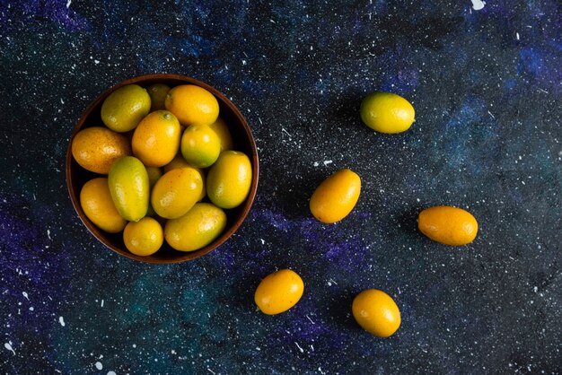 Photo gratuite vue de dessus des kumquats dans un bol en bois