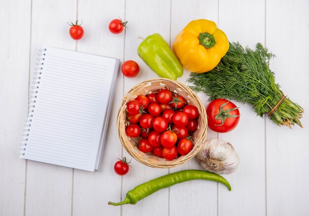 Vue de dessus des légumes comme l'aneth et l'ail tomate poivron avec bloc-notes sur la surface en bois