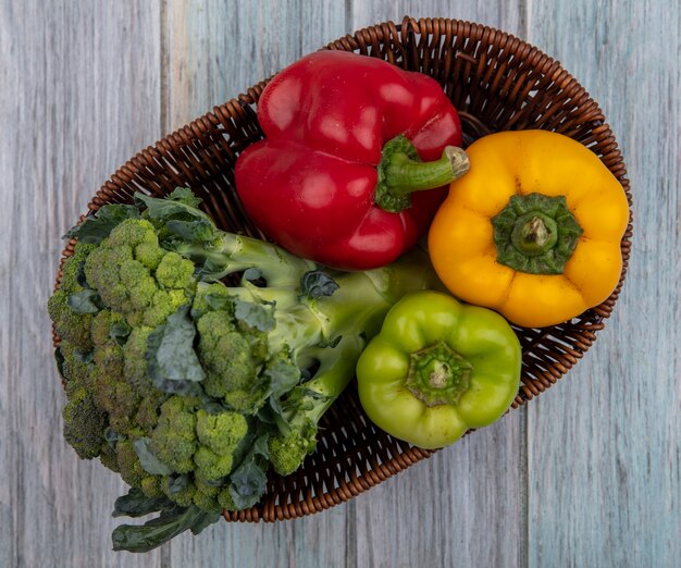 Vue de dessus des légumes comme le brocoli et les poivrons dans le panier sur fond de bois