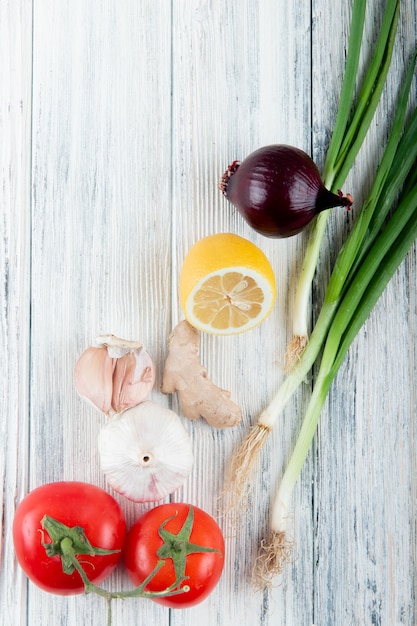 Vue de dessus des légumes comme le gingembre oignon tomate ail au citron sur fond de bois avec copie espace