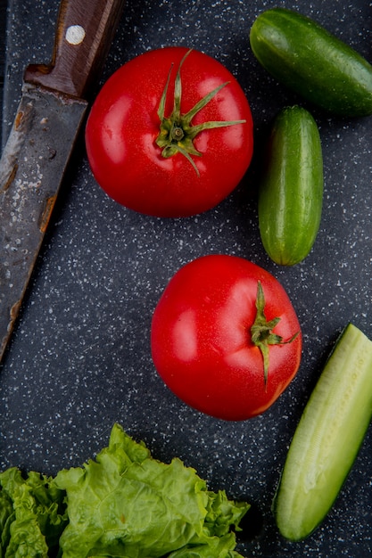 Photo gratuite vue de dessus des légumes comme la laitue de concombre tomate avec couteau sur une planche à découper comme surface