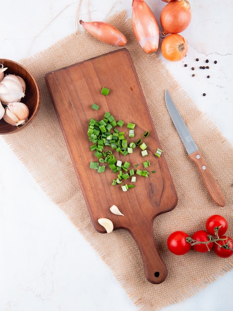 Vue de dessus des légumes comme l'oignon coupé sur une planche à découper tomate à l'ail avec un couteau sur fond blanc avec copie espace