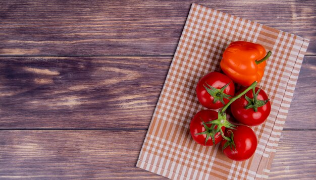 Vue de dessus des légumes comme le poivre et les tomates sur un tissu écossais sur le côté droit et la surface en bois avec copie espace