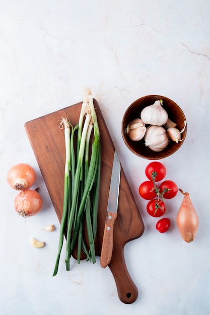 Photo gratuite vue de dessus des légumes comme tomate ail oignon avec couteau sur une planche à découper sur fond blanc avec copie espace