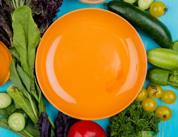 Vue de dessus des légumes comme tomate concombre épinards basilic avec plaque sur bleu