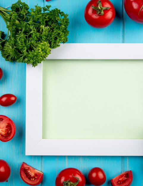 Vue de dessus des légumes comme la tomate et la coriandre autour du conseil d'administration sur la surface bleue avec copie espace