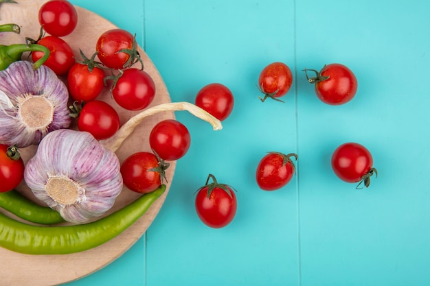 Photo gratuite vue de dessus des légumes comme tomate poivron à l'ail sur une planche à découper sur une surface bleue