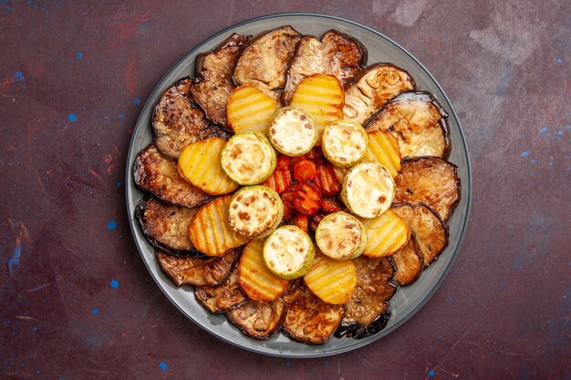 Vue de dessus légumes cuits au four pommes de terre et aubergines à l'intérieur de la plaque sur l'espace sombre