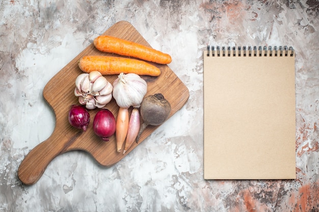 Photo gratuite vue de dessus des légumes frais avec ail et bloc-notes sur fond blanc