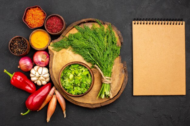 Vue de dessus des légumes frais avec des assaisonnements et des légumes verts sur la surface sombre salade santé repas mûr légume