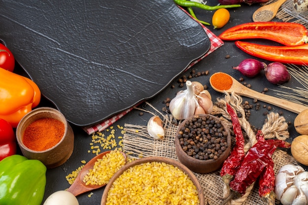 Vue de dessus légumes frais boulgour blé dans un bol épices ail plateau noir sur table