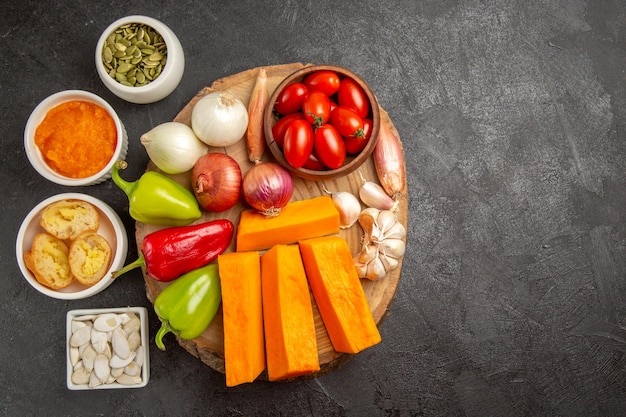 Vue de dessus des légumes frais avec de la citrouille et des graines sur la couleur du repas mûr de la salade de fond sombre