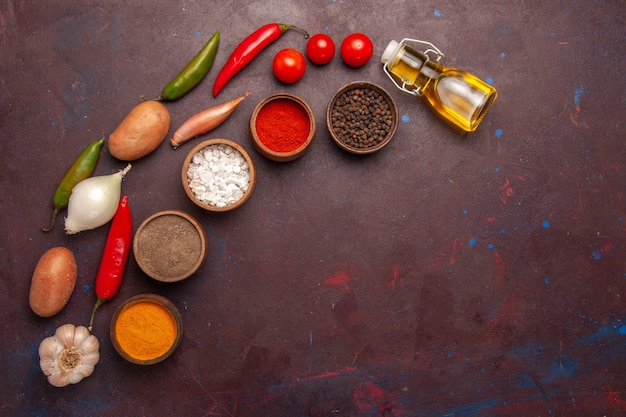 Photo gratuite vue de dessus des légumes frais avec différents assaisonnements sur l'espace sombre