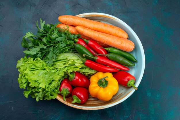 Vue de dessus légumes frais à l'intérieur de la plaque sur le bureau bleu collation déjeuner salade légumes