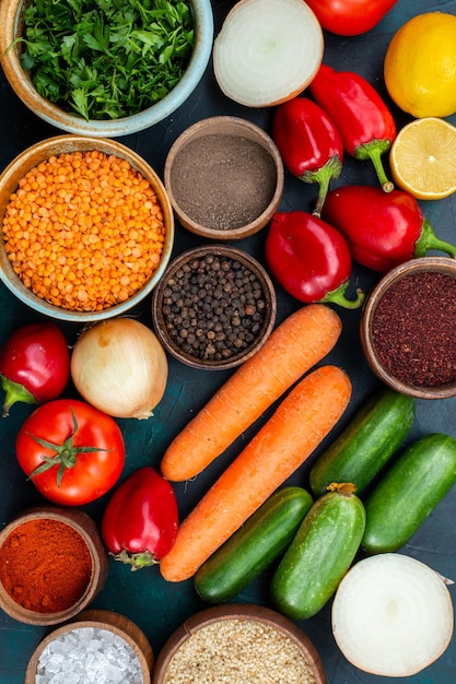 Photo gratuite vue de dessus des légumes frais avec des légumes verts et des assaisonnements sur le bureau bleu foncé.