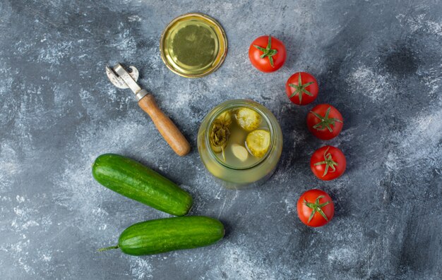 Vue de dessus des légumes frais et marinés. Pot de cornichon ouvert avec tomate fraîche et concombre