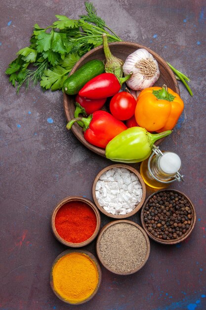 Vue de dessus des légumes frais mûrs avec des légumes verts et des assaisonnements sur une surface sombre repas de salade couleur mûre de légumes