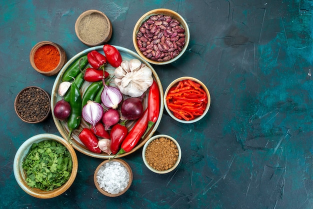 Vue de dessus des légumes frais oignons ail poivrons rouges froids avec des verts sur noir, produit ingrédient de repas alimentaire