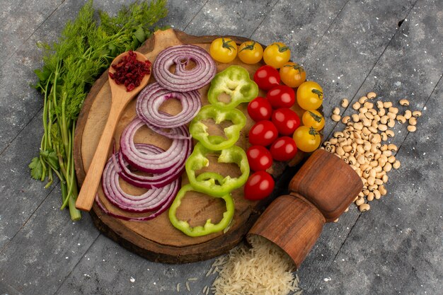 Vue de dessus des légumes frais oignons émincés poivron vert et autres légumes sur le sol gris