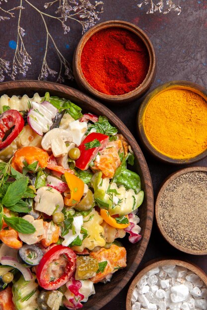 Vue de dessus de légumes frais. salade avec différents assaisonnements sur fond noir