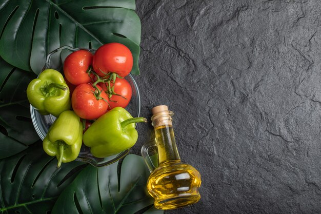 Vue De Dessus Des Légumes Frais, De La Tomate Et Du Poivre Dans Un Bol En Verre Et Une Bouteille D'huile.