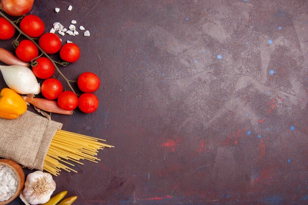 Vue de dessus légumes frais tomates oignons pâtes et pommes de terre sur un espace sombre