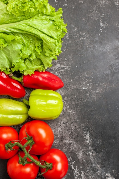 Vue de dessus légumes frais tomates poivrons verts et rouges laitue sur place libre surface sombre