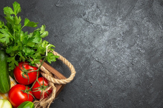 Vue de dessus des légumes frais, tomates rouges, concombres et courges avec des verts sur la surface grise