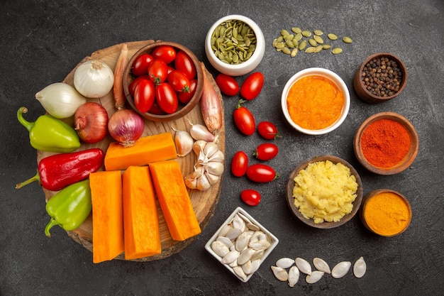 Vue de dessus des légumes frais avec des tranches de citrouille et de l'ail sur fond gris graine de couleur salade mûre fraîche