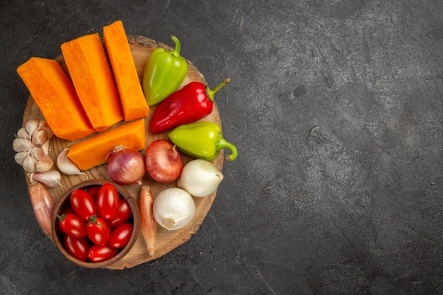 Vue de dessus des légumes frais avec des tranches de citrouille sur fond gris foncé couleur mûre fraîche