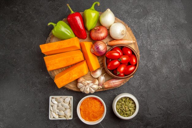 Vue de dessus des légumes frais avec des tranches de citrouille sur la salade mûre de graines fraîches de couleur de fond gris