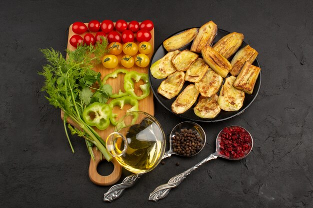 Vue de dessus des légumes frais tranchés et entiers avec de l'huile d'olive sur le fond gris