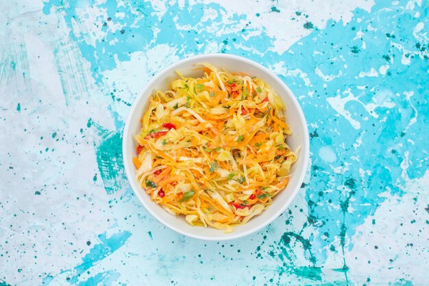 Vue de dessus légumes frais en tranches longues et fines salade en morceaux à l'intérieur de la plaque ronde sur le fond bleu salade de légumes repas alimentaire