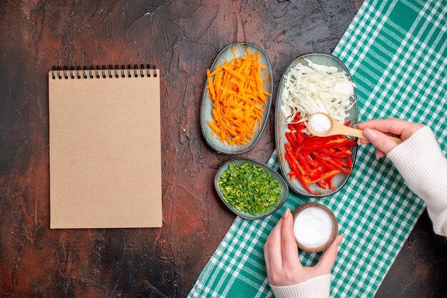 Vue de dessus légumes tranchés chou carotte et poivron avec des verts sur table sombre