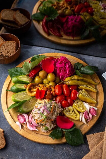 Une vue de dessus des légumes en tranches et des laitues de concombres entiers sur le bureau en bois brun avec des miches de pain sur le bureau gris vitamines