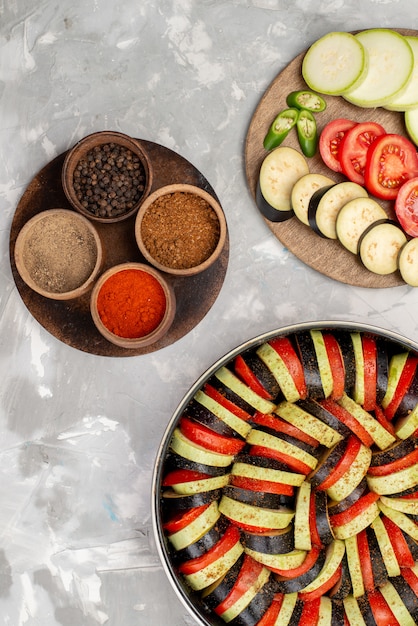 Vue de dessus des légumes tranchés tels que les tomates et les aubergines frais et cuits sur le bureau lumineux repas de légumes frais mûrs