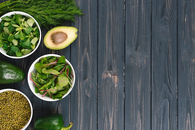 Photo gratuite une vue de dessus de légumes verts sur un bureau en bois noir