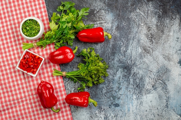Vue de dessus des légumes verts frais avec des poivrons rouges sur la table gris clair